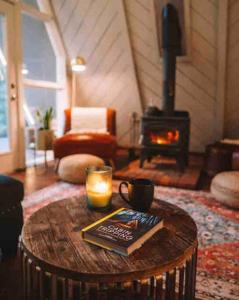 a living room with a table with a book and a fireplace at Aframe of Mind Packwood in Packwood