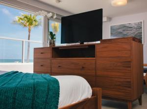 a bedroom with a large dresser with a television on it at Tides Inn Hotel in Fort Lauderdale