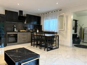 a kitchen with black cabinets and a table and chairs at Proche Gare Paris-CDG Stade-de-France Astérix Expo in Garges-lès-Gonesse