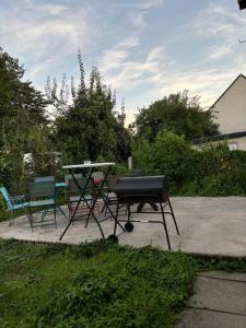 a grill and a table and chairs in a yard at Proche Gare Paris-CDG Stade-de-France Astérix Expo in Garges-lès-Gonesse