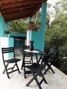 a black table with two chairs and a vase on it at Casa de Praia Massaguaçu! Ao meio Áreas Arborizadas in Caraguatatuba