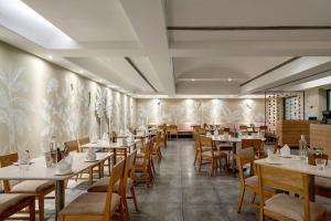 a restaurant with tables and chairs in a room at Greenpark Visakhapatnam in Visakhapatnam