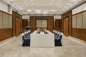 a conference room with a white table and blue chairs at Greenpark Visakhapatnam in Visakhapatnam