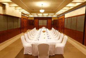 a conference room with a long table and white chairs at Greenpark Visakhapatnam in Visakhapatnam
