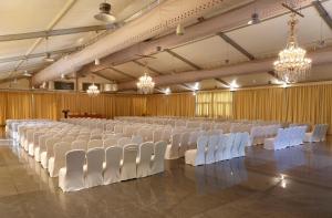 a large hall with rows of white chairs and chandeliers at Greenpark Visakhapatnam in Visakhapatnam