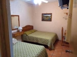 a small room with two beds and a mirror at Hotel Casa Galena in Morelia