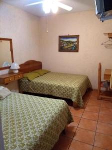 a hotel room with two beds and a tv at Hotel Casa Galena in Morelia