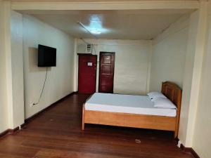 a small bedroom with a bed and a flat screen tv at starlight lodging house in Laoag