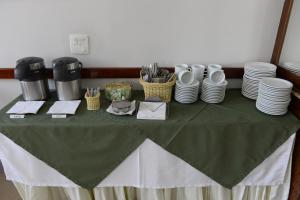 a table with a green table cloth and plates on it at Hotel Colonial Plaza in Itu