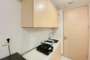 eine Küche mit weißen Schränken und einer Waage auf einer Theke in der Unterkunft Studio Furnished with Comfort Design at Tokyo Riverside PIK 2 Apartment By Travelio in Rawalembang