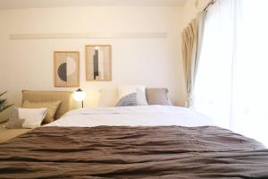 Un dormitorio con una cama grande y una ventana. en コーポぱぱどれ103, en Tokio