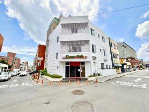 a white building on a street with a sign on it at Slow Citi Guest House -슬로시티게스트하우스 in Seogwipo