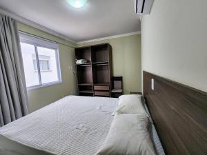 ein Schlafzimmer mit einem Bett und einem Fenster in der Unterkunft Acrópole Residence in Bombinhas + 49 Fotos