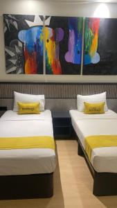 two beds in a room with paintings on the wall at Kostello Rajawali in Palembang