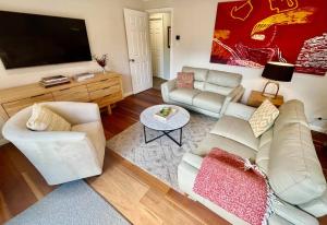 a living room with a couch and a flat screen tv at The Cricket House - Family & Pet-Friendly Home in Bowral