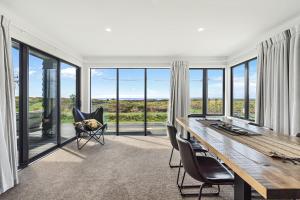 una sala da pranzo con tavolo, sedie e finestre di Beachfront Paradise - Papamoa Beach Holiday Home a Papamoa
