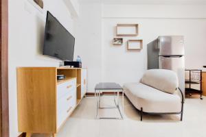 a living room with a chair and a flat screen tv at Comfort Stay 2BR at Loftvilles City Apartment By Travelio in Tangerang