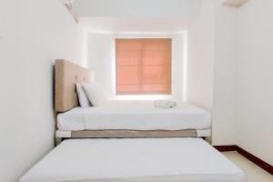 two beds in a room with a window at Comfort Stay 2BR at Loftvilles City Apartment By Travelio in Tangerang +11 photos