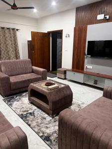 a living room with couches and a flat screen tv at SAHARHOMEstay O3 in Mysore