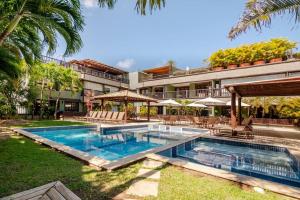a swimming pool in front of a building at PRAIA DO FORTE CONDOMINIO KAUAI in Praia do Forte
