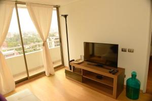 ein Wohnzimmer mit einem Flachbild-TV und einem großen Fenster in der Unterkunft Chilean Suites Providencia II in Santiago