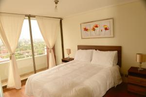 ein Schlafzimmer mit einem weißen Bett und einem Fenster in der Unterkunft Chilean Suites Providencia II in Santiago