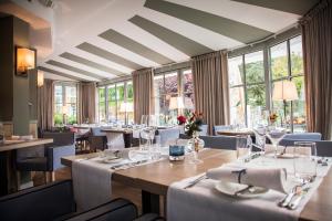 ein Esszimmer mit Tischen, Stühlen und Fenstern in der Unterkunft Tandreas Hotel & Restaurant in Gießen