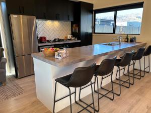 a kitchen with a large island with bar stools at Pedal and Play - Cromwell Holiday Home in Cromwell +2 photos