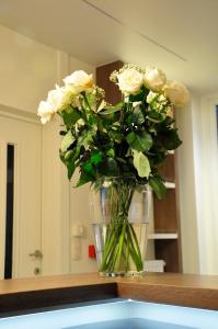 a vase filled with white roses sitting on a counter at Hotel Brasserie De Beiaard in Torhout