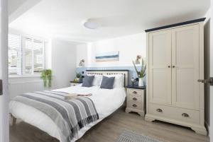 Un dormitorio blanco con una cama y un armario. en Offshore, Carbis Bay, St Ives, en Carbis Bay