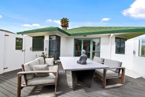 a patio with a table and chairs and a house at Fernwood Escape - Tauranga Holiday Home in Tauranga