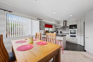 a kitchen and dining room with a table and chairs at Fernwood Escape - Tauranga Holiday Home in Tauranga +8 photos