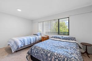 two beds in a bedroom with a window at Fernwood Escape - Tauranga Holiday Home in Tauranga