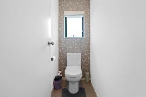 a bathroom with a toilet and a window at Fernwood Escape - Tauranga Holiday Home in Tauranga