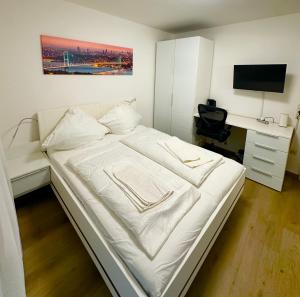 a bedroom with a white bed and a desk with a computer at Tolle FeWo direkt am Campus 24-7 Checkin in Germersheim