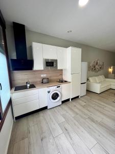 a kitchen with white cabinets and a washer and dryer at Califa SuitesGP in Córdoba
