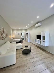 a living room with a white couch and a tv at Califa SuitesGP in Córdoba