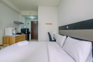 Un dormitorio con una gran cama blanca con almohadas blancas. en Comfy and Modern Studio Transpark Cibubur Apartment By Travelio, en Depok 17 fotos más