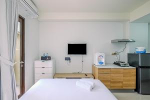 Un dormitorio con una cama blanca y un televisor. en Comfy and Modern Studio Transpark Cibubur Apartment By Travelio, en Depok