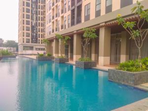 una piscina de agua azul frente a un edificio en Comfy and Modern Studio Transpark Cibubur Apartment By Travelio, en Depok