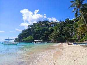 a beach with two boats in the water at Tropicana Ocean Villas in Boracay