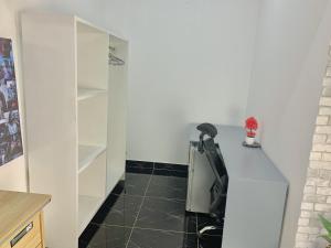 a kitchen with white cabinets and a black tile floor at Studio Le Parisien in Pointe-Noire