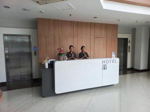 two people standing at a hotel reception desk at Hotel 88 Kedoya Jakarta in Jakarta
