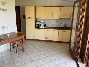 kuchnia z żółtymi szafkami, stołem i biurkiem w obiekcie Casa Vacanze Residence I delfini w mieście Badesi +12 zdjęć