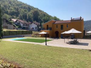 a house with a yard with umbrellas and a pool at VILLA VALLE FRANCIACORTA - Appartamenti per vacanze in Rodengo Saiano