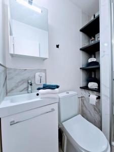 a white bathroom with a toilet and a sink at Escale Alpine Appartement moderne avec parking proche Annecy et ski in Ugine +8 photos