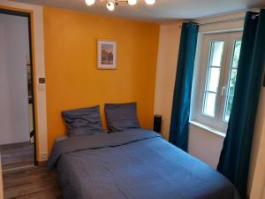 a bedroom with a bed and a window with blue curtains at Mont saint michel normandie in Sainte-Cécile