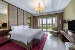 une chambre avec un lit, un bureau et une télévision dans l'établissement Al Habtoor Polo Resort, à Dubaï