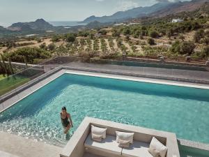 a woman standing in the water in a swimming pool at Hue Villa, Stunning Southern Beaches, By ThinkVilla in Asómatoi