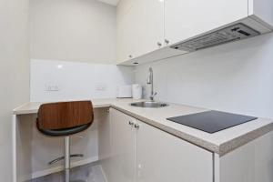 a white kitchen with a sink and a chair at 95 Studios in London